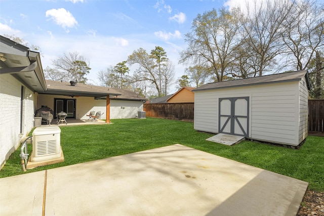 view of yard with an outbuilding, a fenced backyard, a shed, and a patio area