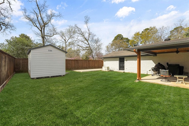 view of yard with a patio, an outbuilding, a ceiling fan, a fenced backyard, and a storage unit