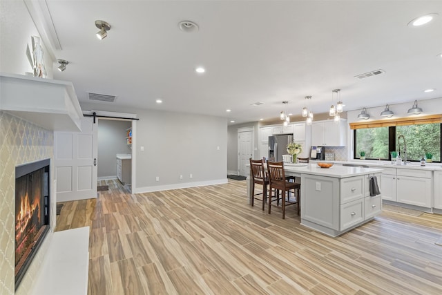 kitchen featuring a barn door, stainless steel refrigerator with ice dispenser, visible vents, and a kitchen island