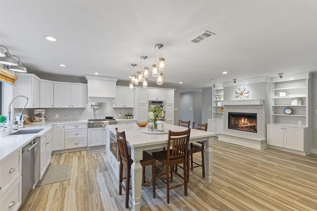 kitchen featuring visible vents, a tiled fireplace, light countertops, appliances with stainless steel finishes, and a sink