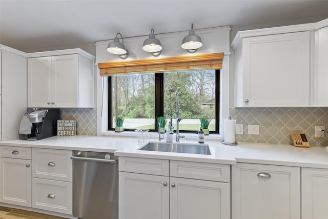 kitchen featuring a sink, stainless steel dishwasher, white cabinets, and light countertops