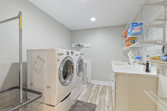 washroom with baseboards, light wood finished floors, laundry area, a sink, and washer and clothes dryer