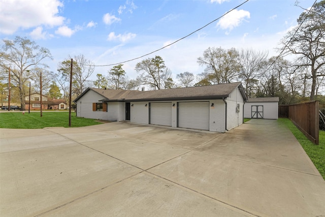 garage featuring a storage shed, concrete driveway, and fence