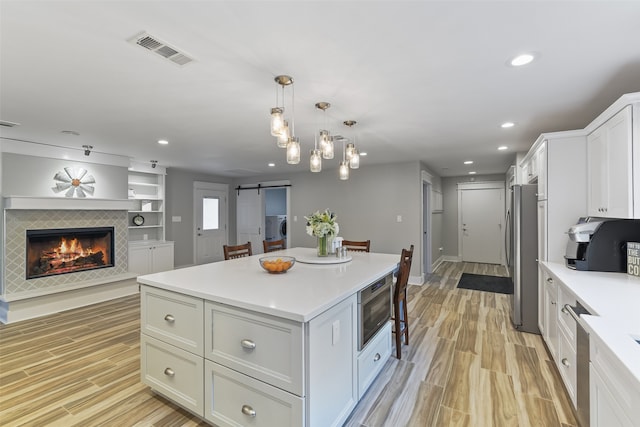 kitchen featuring visible vents, a kitchen island, freestanding refrigerator, a barn door, and open floor plan