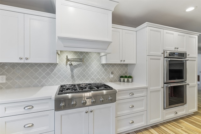 kitchen featuring appliances with stainless steel finishes, white cabinets, and light countertops