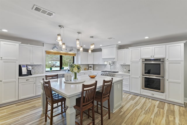 kitchen featuring light wood-type flooring, visible vents, stainless steel appliances, white cabinets, and light countertops