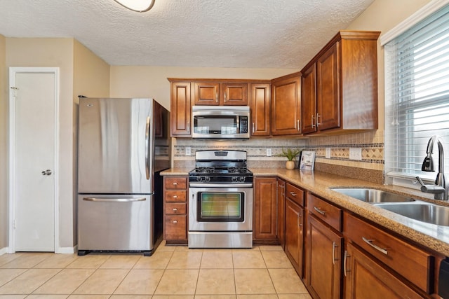 kitchen featuring a sink, backsplash, appliances with stainless steel finishes, and light tile patterned flooring