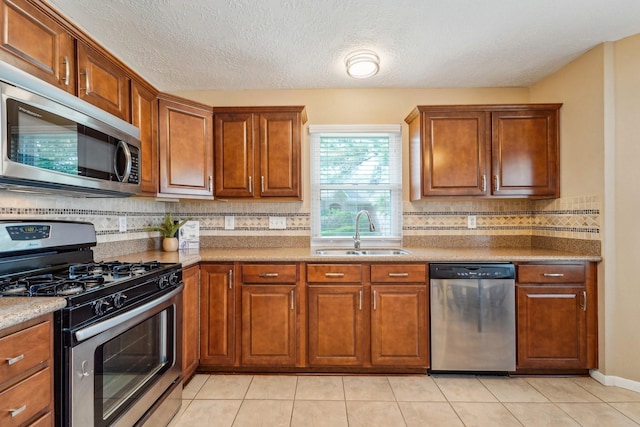 kitchen featuring backsplash, brown cabinets, appliances with stainless steel finishes, and a sink