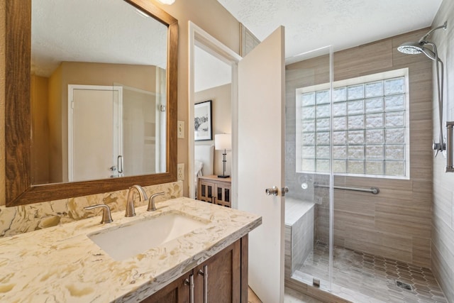 bathroom featuring a stall shower, a textured ceiling, and vanity