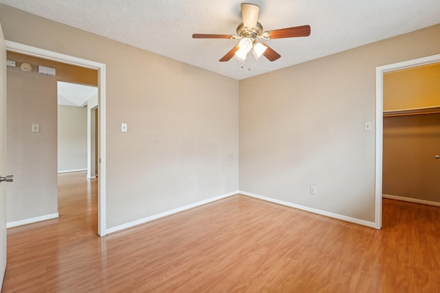 unfurnished bedroom with a walk in closet, wood finished floors, baseboards, and a closet