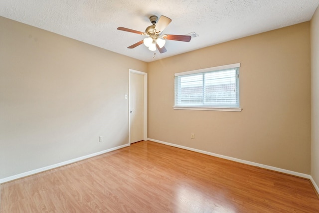 spare room featuring ceiling fan, a textured ceiling, baseboards, and light wood-style floors