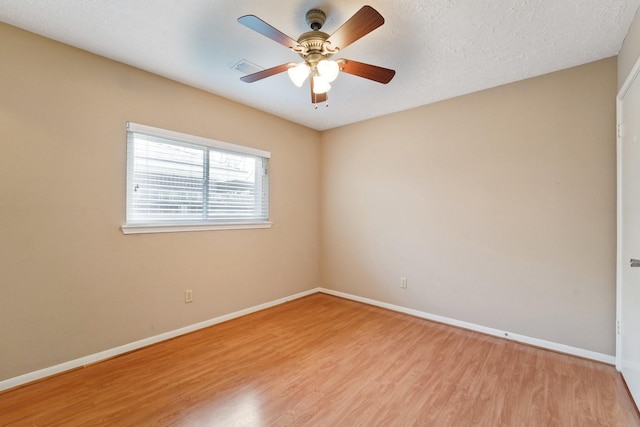 empty room featuring a ceiling fan, visible vents, baseboards, light wood-style floors, and a textured ceiling