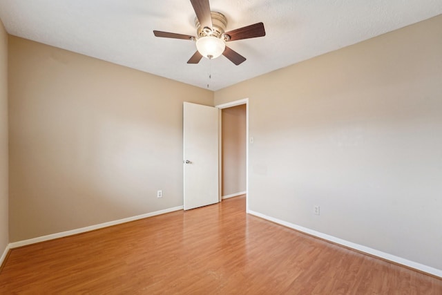 spare room with baseboards, light wood-style floors, and ceiling fan