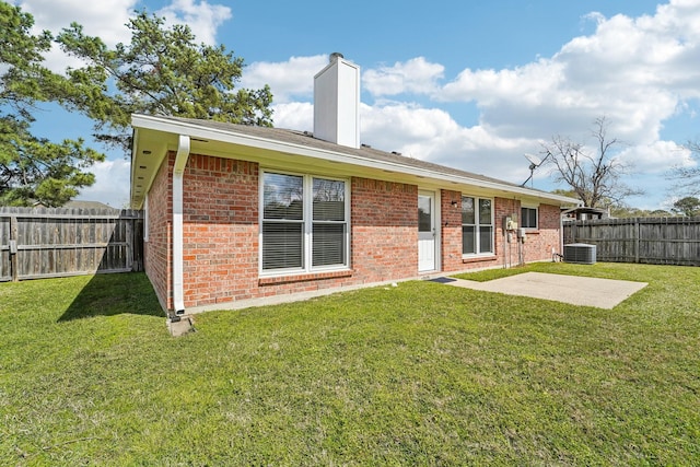 rear view of house featuring a lawn, central AC unit, and a fenced backyard