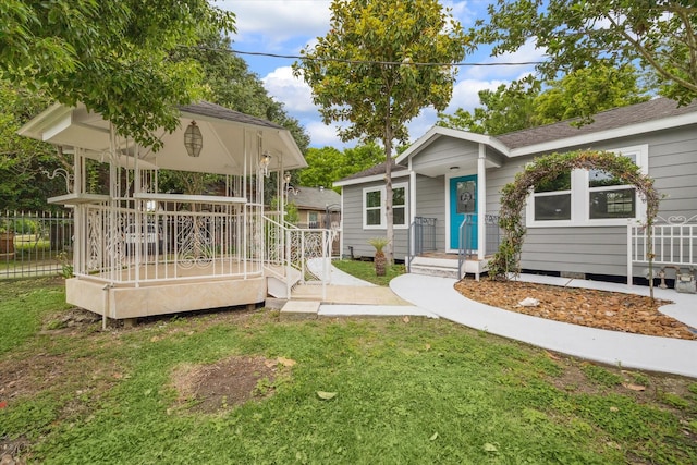 view of front of house featuring a gazebo, a front lawn, and fence