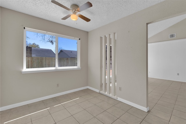 empty room featuring light tile patterned floors, visible vents, a textured ceiling, and a ceiling fan