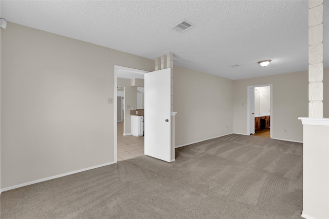 carpeted empty room featuring baseboards, visible vents, and a textured ceiling