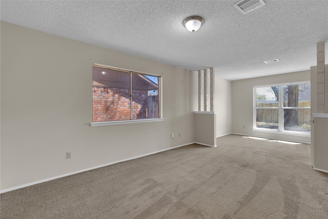 empty room with visible vents, a textured ceiling, baseboards, and carpet floors