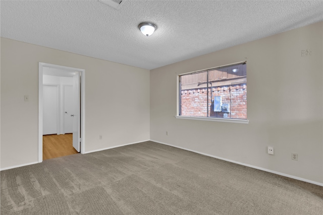 carpeted empty room featuring baseboards and a textured ceiling