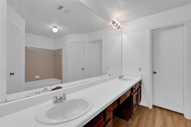 full bathroom with double vanity, visible vents, wood finished floors, and a sink