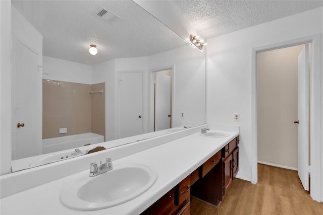 bathroom with a sink, visible vents, wood finished floors, and double vanity