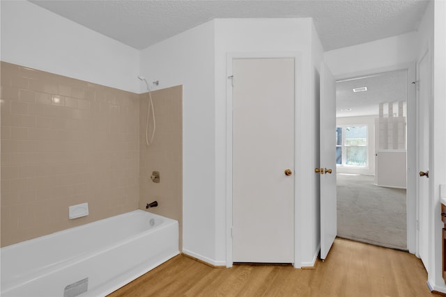 full bath featuring shower / tub combination, wood finished floors, and a textured ceiling