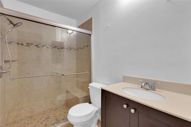 full bathroom featuring toilet, a stall shower, vanity, and a textured ceiling