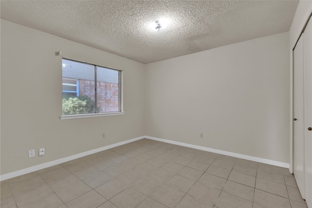 unfurnished room with light tile patterned floors, baseboards, and a textured ceiling