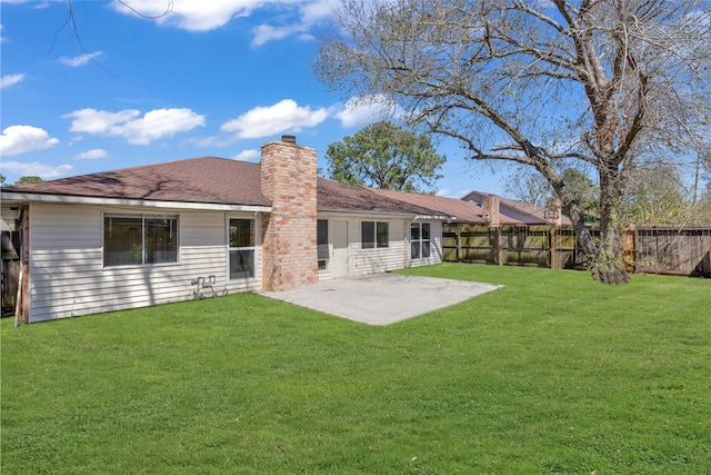 rear view of house featuring a yard, a patio, a chimney, and a fenced backyard