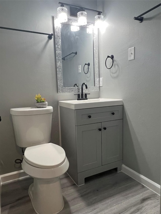 bathroom featuring vanity, toilet, wood finished floors, and baseboards