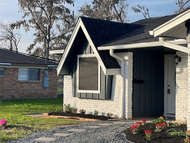 property entrance with a lawn, board and batten siding, and roof with shingles