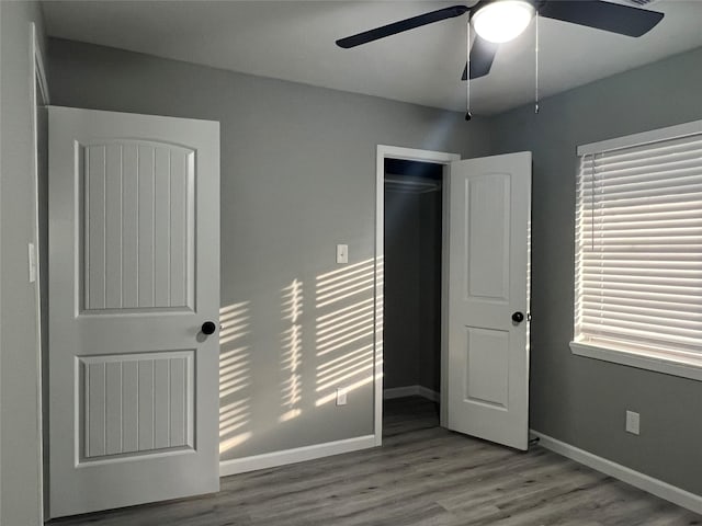 unfurnished bedroom with a closet, ceiling fan, baseboards, and wood finished floors