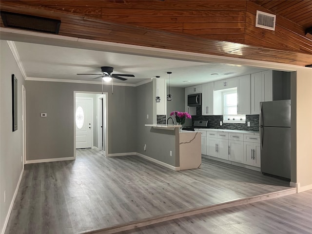 kitchen with visible vents, black stove, freestanding refrigerator, a peninsula, and crown molding