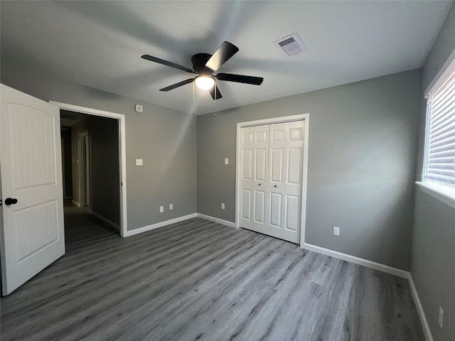 unfurnished bedroom featuring visible vents, baseboards, a closet, and wood finished floors