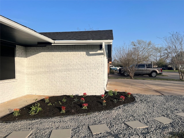 view of home's exterior featuring brick siding and roof with shingles