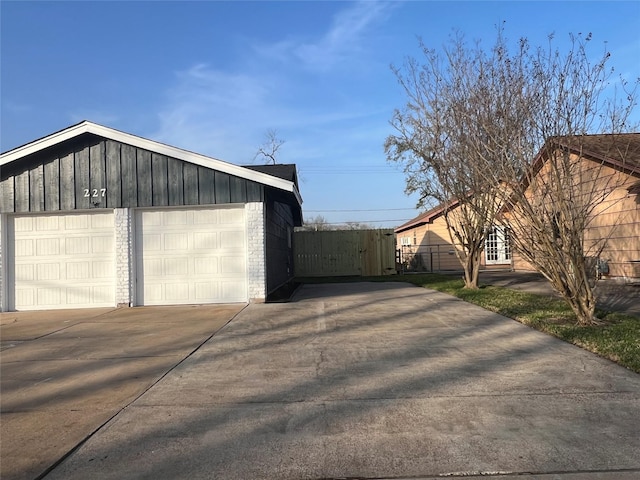 garage with concrete driveway and fence