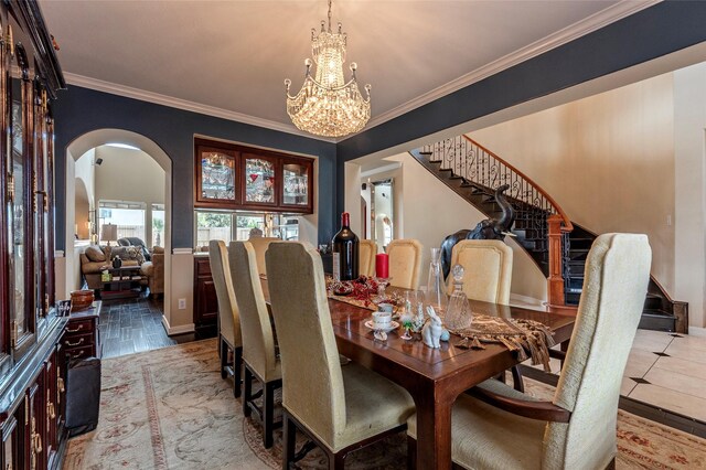 tiled dining area with stairs, an inviting chandelier, crown molding, and arched walkways