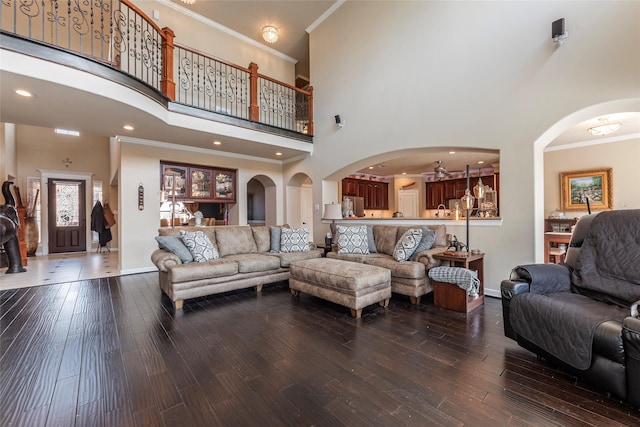 living area featuring ornamental molding, wood finished floors, baseboards, and arched walkways