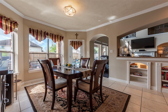 dining room featuring crown molding, light tile patterned floors, arched walkways, and plenty of natural light