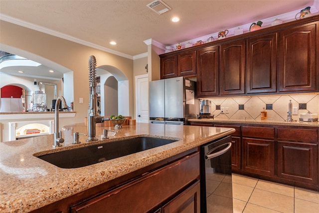 kitchen featuring light stone counters, arched walkways, freestanding refrigerator, decorative backsplash, and dishwasher