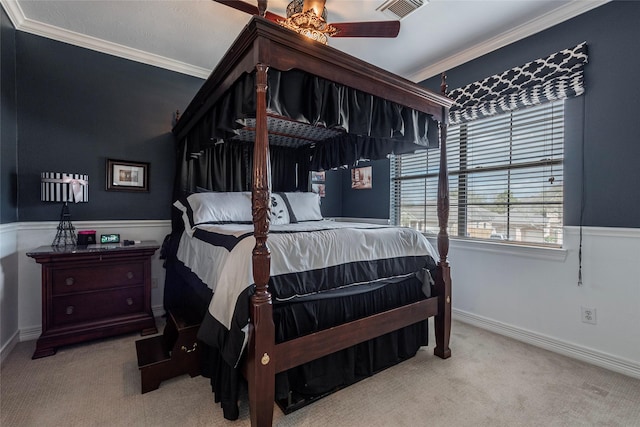 carpeted bedroom featuring crown molding, a ceiling fan, a wainscoted wall, and visible vents