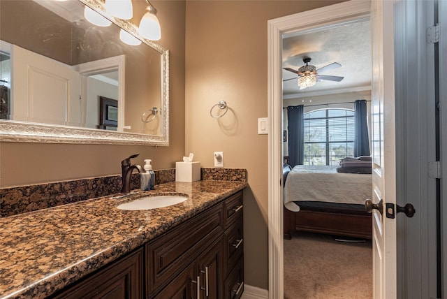 bathroom with connected bathroom, crown molding, baseboards, ceiling fan, and vanity