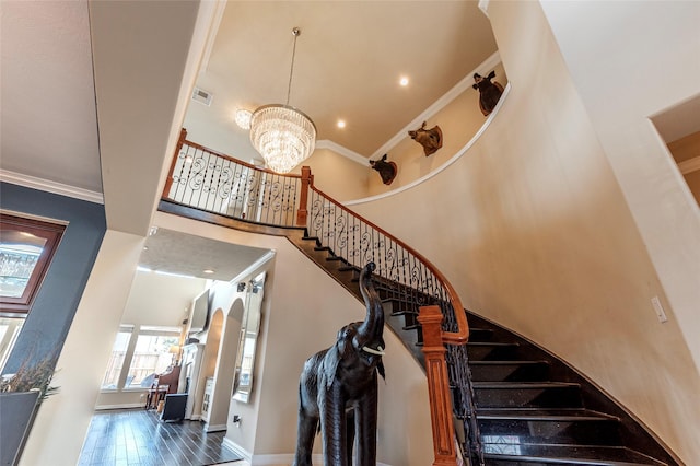 stairway featuring an inviting chandelier, wood finished floors, a towering ceiling, and ornamental molding