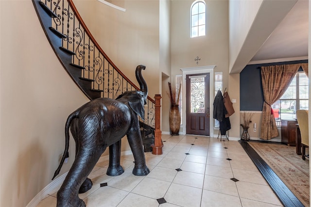 tiled foyer with stairway, plenty of natural light, and a high ceiling