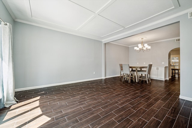 unfurnished dining area featuring wood finish floors, a notable chandelier, ornamental molding, arched walkways, and baseboards