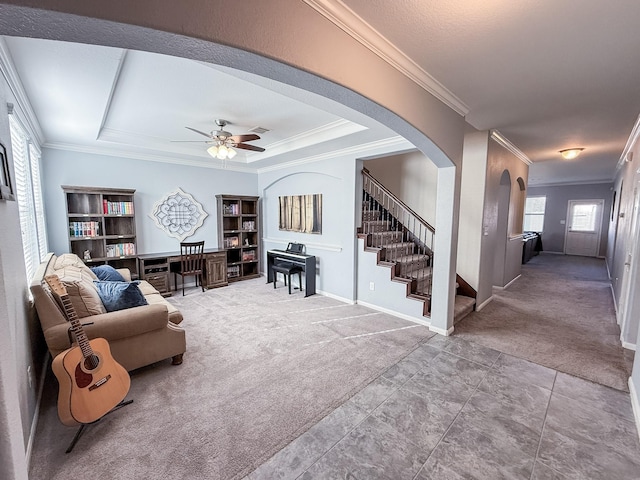 carpeted living room with arched walkways, stairway, ceiling fan, and ornamental molding