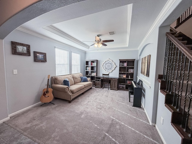 living room featuring a ceiling fan, visible vents, ornamental molding, light carpet, and a raised ceiling