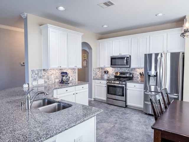 kitchen with visible vents, stainless steel appliances, arched walkways, white cabinetry, and a sink