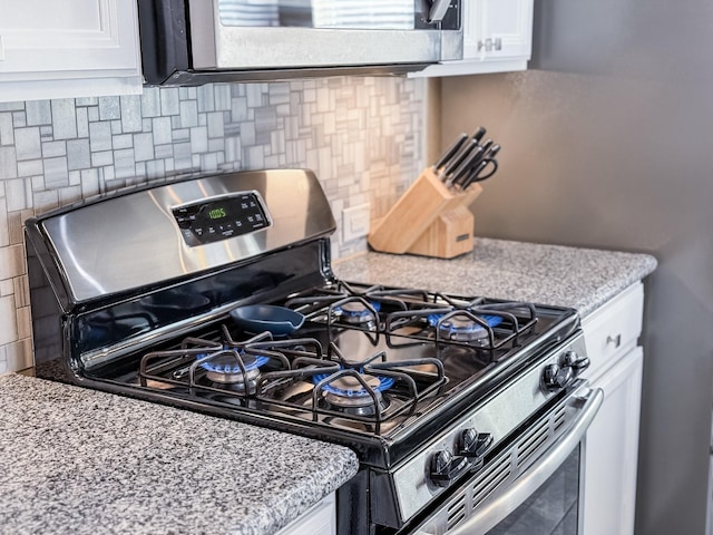 kitchen with stainless steel appliances, light stone countertops, white cabinets, and decorative backsplash