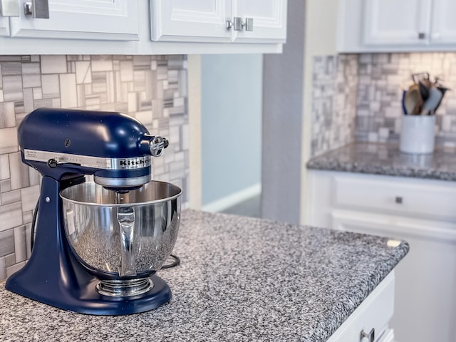 details featuring decorative backsplash, white cabinetry, and dark stone counters